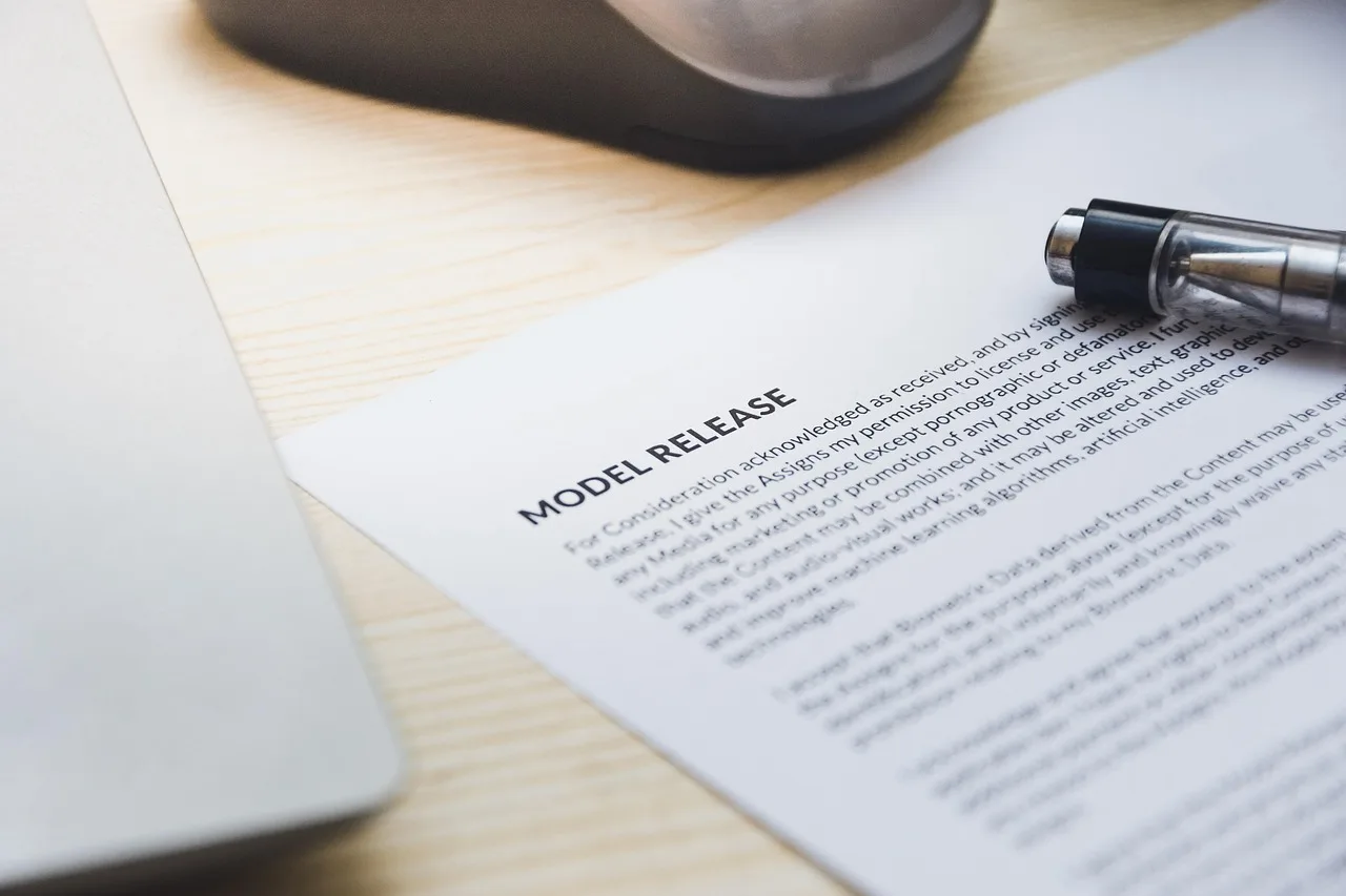 paper, model release, form, document, signing, pen, desk, agreement, business, contract, signature. Creator collaboration problems: rights and image use